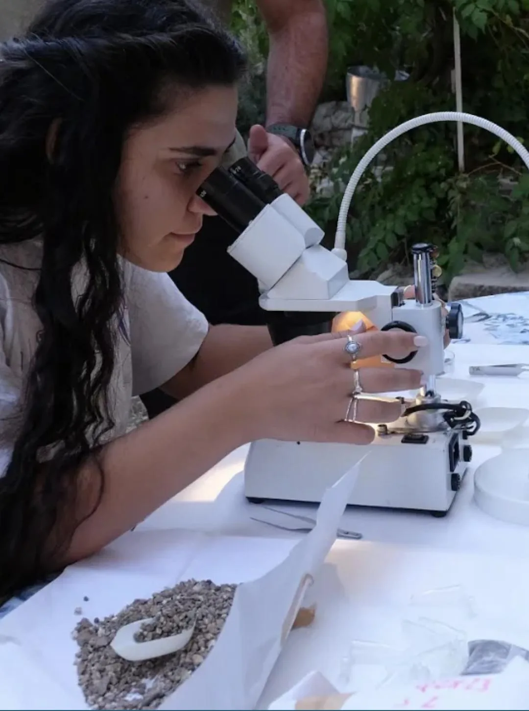 Archeologa che esamina materiale archeobotanico allo stereomicroscopio